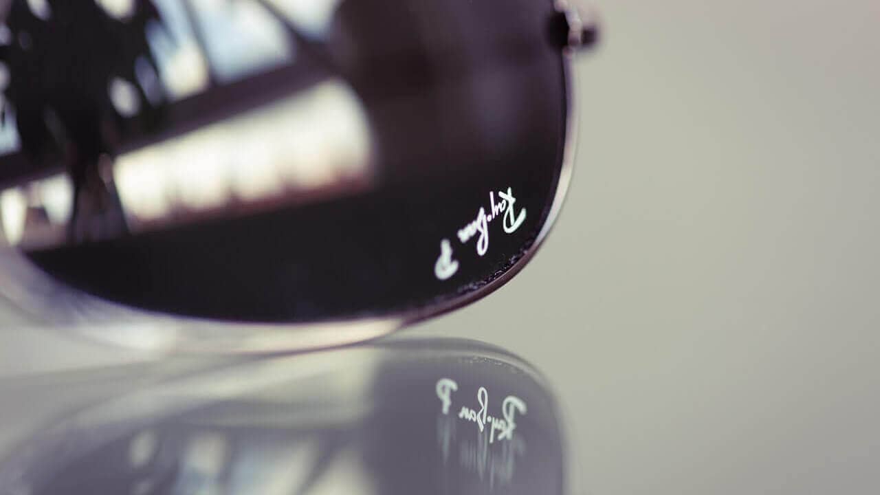 Ray Ban-Logo auf Brille, das sich auf einem Tisch spiegelt