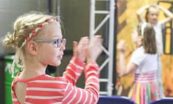 Kurzsichtigkeit bei Kindern - Mädchen mit Brille applaudiert