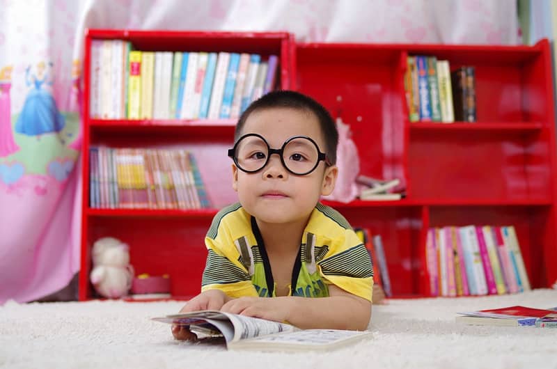 Kurzsichtigkeit bei Kindern - Junge mit Brille vor rotem Regal